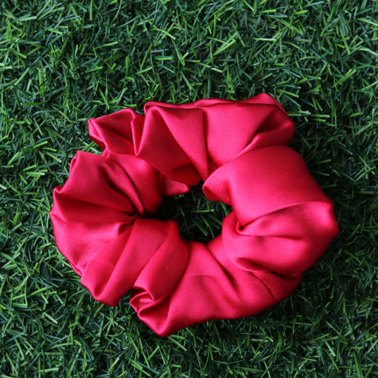 Red scrunchie on green grass